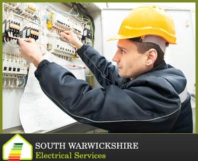 electrician with a hard hat testing a fuse box